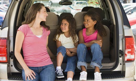 mother and two girls sitting in back of van